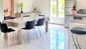 Eine moderne Küche mit Essbereich, ausgestattet mit einem großen Tisch, Stühlen und einem Kühlschrank.
