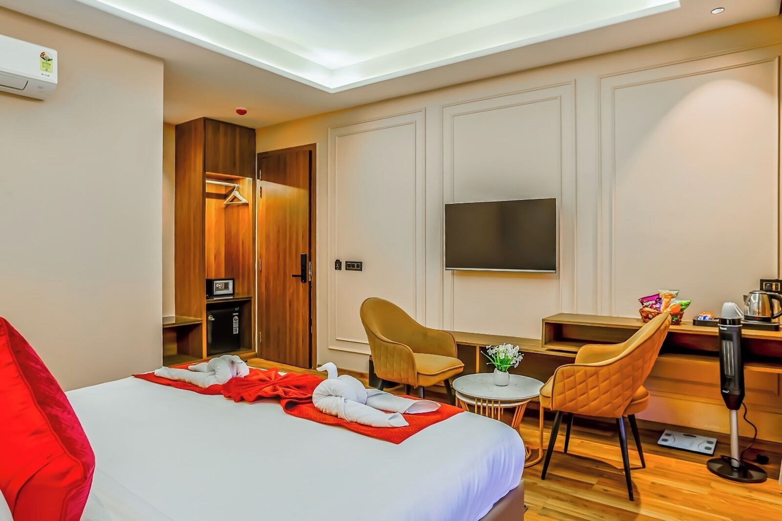 A hotel room with a bed, a desk, a chair, a TV, and a wardrobe.