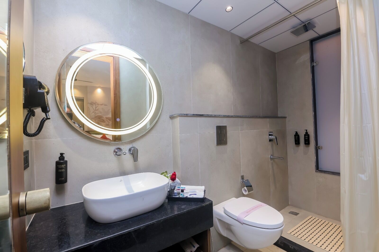 A modern bathroom with a round mirror, a white sink, and a toilet.