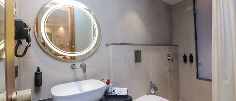A modern bathroom with a round mirror, a white sink, and a toilet.
