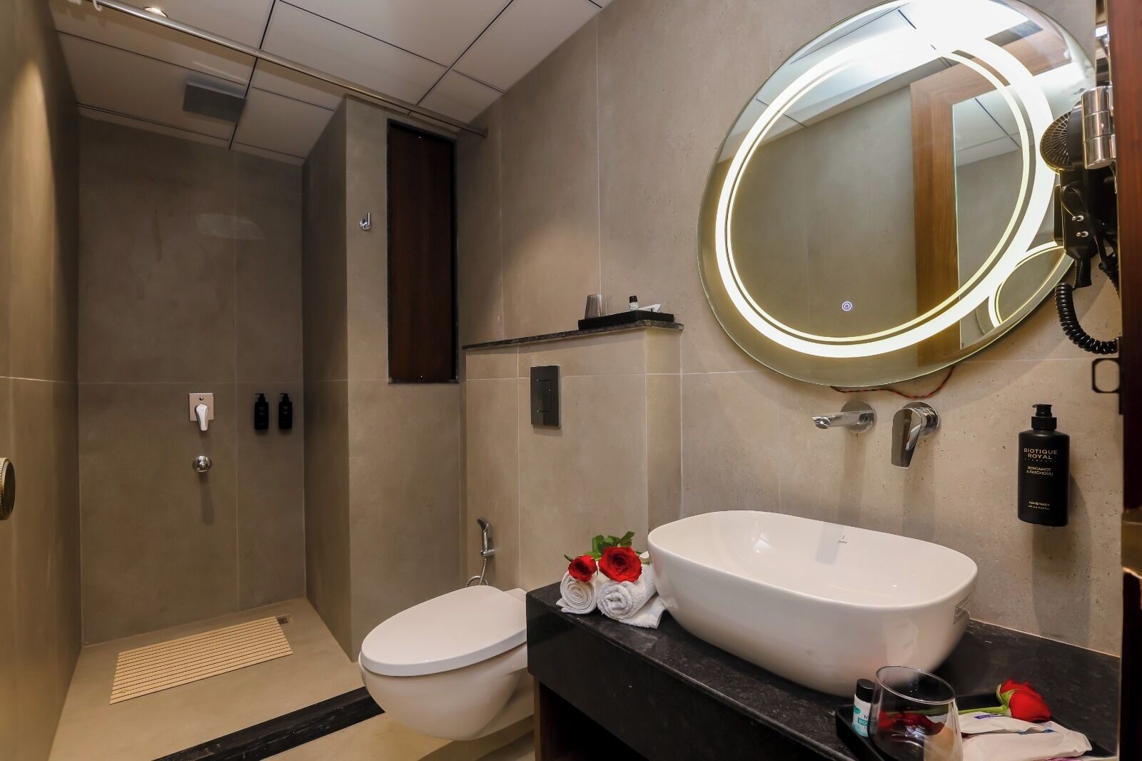 A modern bathroom with a walk-in shower, a toilet, a sink with a large mirror, and toiletries on the counter.