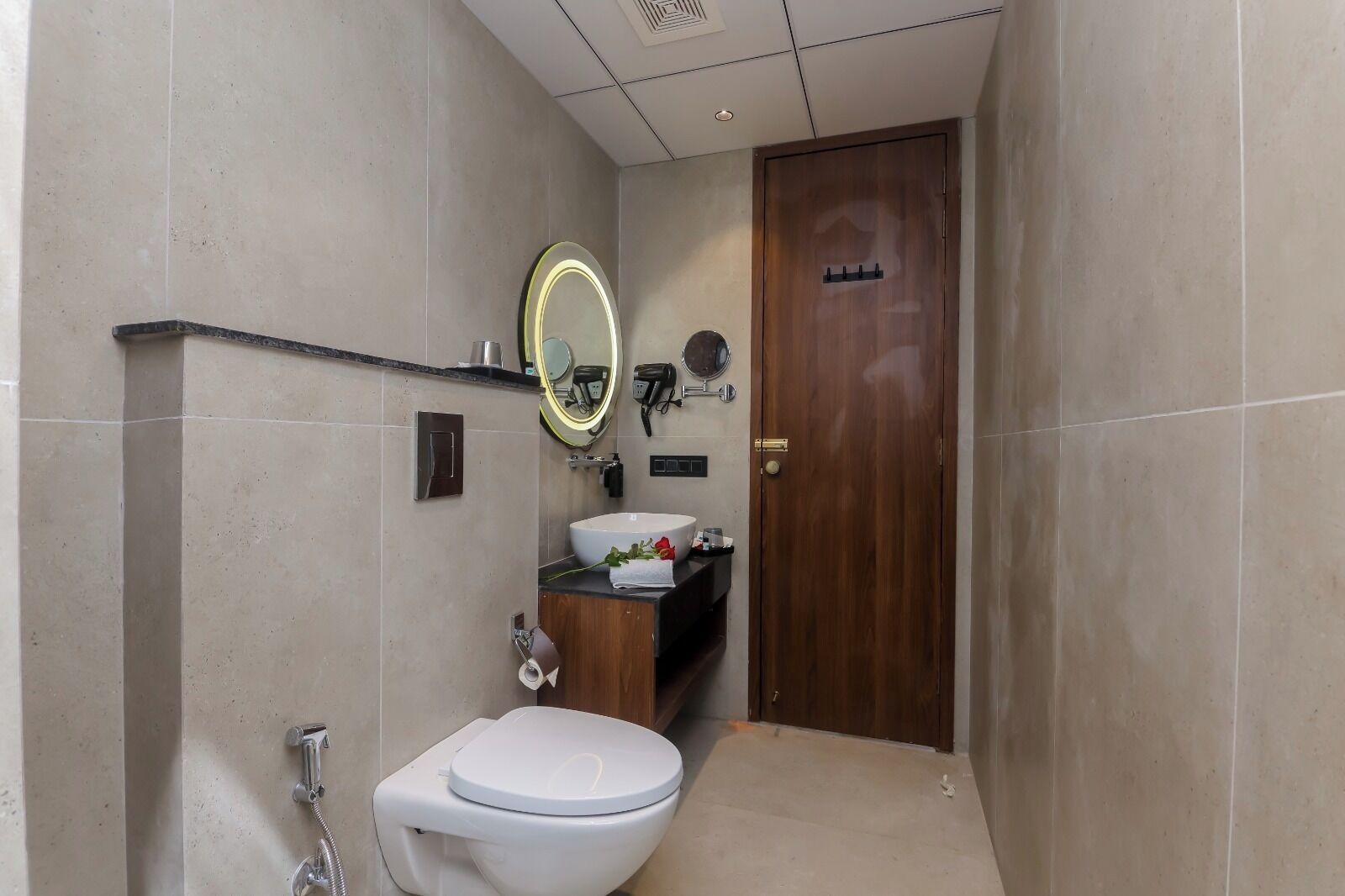 Un baño con inodoro, lavamanos y espejo con iluminación.