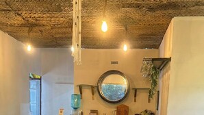 Ein gemütliches Café-Interieur mit Holztischen und -stühlen, einem runden Spiegel an der Wand und einer hängenden Leuchte.