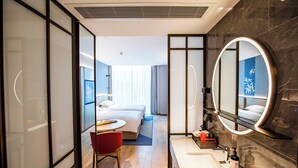 A modern hotel room with a bed, bedside table, chair, and a large mirror. - ECHENG Hotel  (Luoyang)