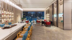 A modern hotel lobby with a long reception desk, seating area, and a view of the cityscape. - ECHENG Hotel  (Luoyang)