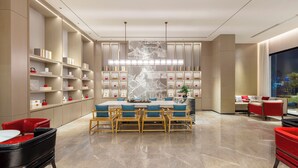 A modern hotel lobby with a central dining area, a large wall-mounted artwork, and a city view through a large window. - ECHENG Hotel  (Luoyang)