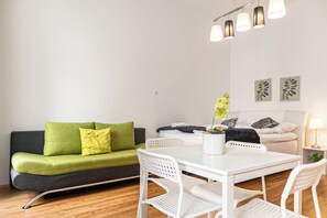 A modern living room with a sofa, a dining table, chairs, a lamp, and artwork on the wall. - Charming 2BR Apt Prime City Spot (Vienna)