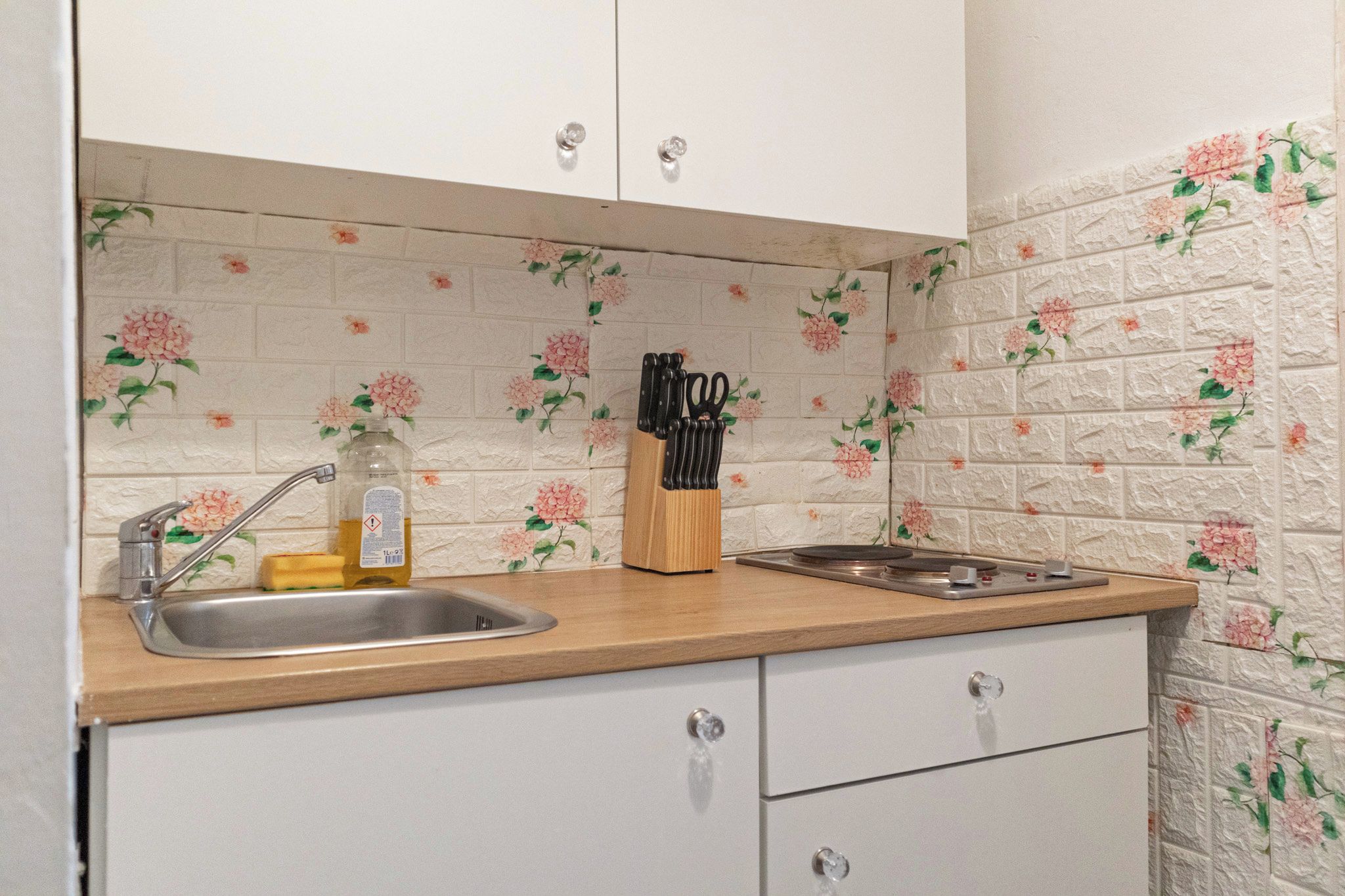 A kitchen with a sink, a bottle of dish soap, and a knife block.