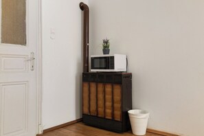 A corner of a room with a white door, a radiator, a microwave, and a white trash bin. - Charming 2BR Apt Prime City Spot (Vienna)