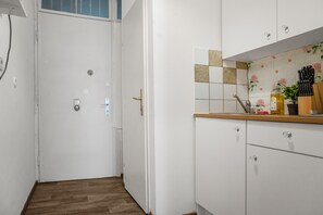 A kitchen with white cabinets, a wooden countertop, and a tiled backsplash with floral patterns. - Charming 2BR Apt Prime City Spot (Vienna)