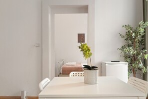 A minimalist room with a white table, a potted plant, and a bed with a pink blanket. - Charming 2BR Apt Prime City Spot (Vienna)