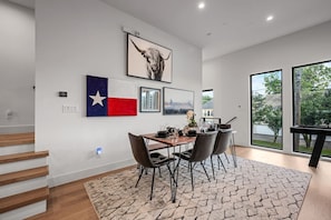 Ett modernt matområde med ett träbord, svarta stolar och en Texas-flagga.