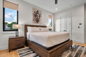 A bedroom with a bed, bedside tables, a window, and a door.