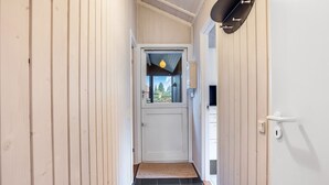 En smal hall med träväggar, ett svart klinkergolv, en vit dörr och en satellitmottagare som är monterad på väggen.