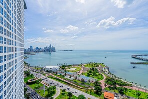 Un hôtel de grande hauteur offrant une vue imprenable sur le paysage urbain côtier, avec un port de plaisance, des routes et des espaces verts.
