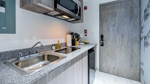 Eine moderne Küche mit Granit Arbeitsplatte, Edelstahl-Spüle und einer Mikrowelle über dem Kochfeld.
