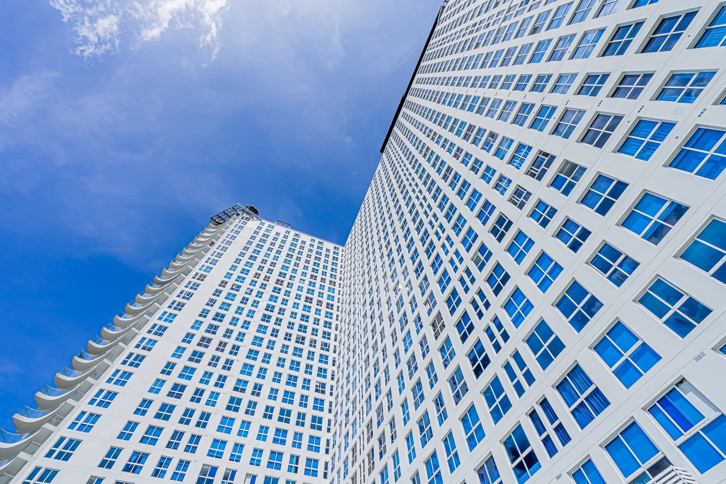 Un edificio alto y moderno con una rejilla de ventanas y un cielo azul despejado al fondo.