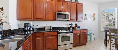 A kitchen with wooden cabinets, a stainless steel stove, a microwave, and a coffee maker.