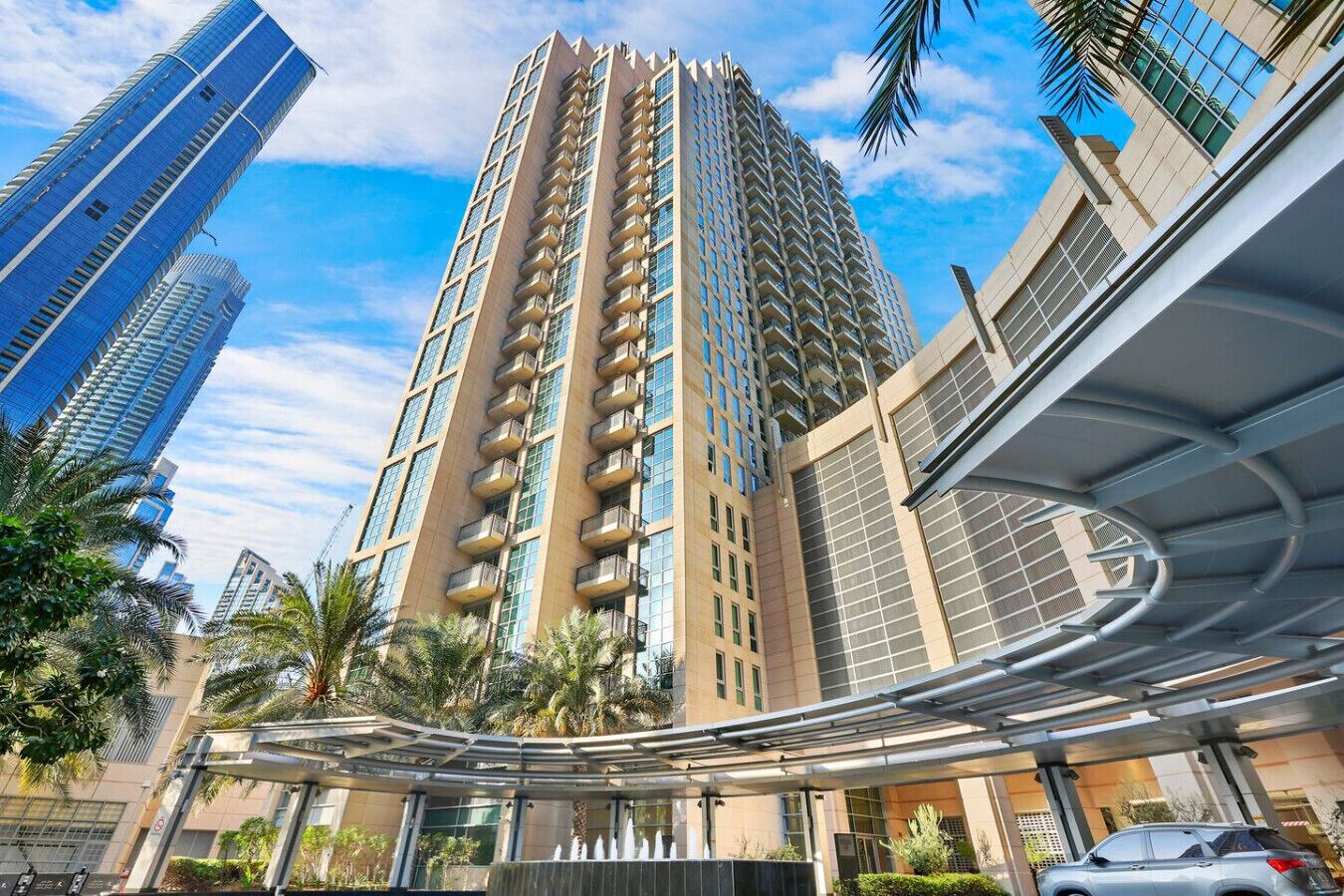A high-rise building with a modern design, featuring a curved glass facade and multiple balconies.