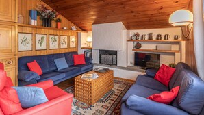 Un salon chaleureux avec des murs en bois, une cheminée et un téléviseur.