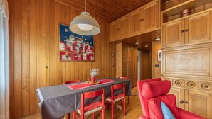 Une pièce aux murs lambrés, avec une table à manger, des chaises et un canapé rouge.