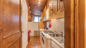 Une cuisine compacte avec des meubles en bois, un lave-linge et un pare-feu en carreaux.