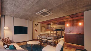 A modern living room with a sofa, chairs, a dining table, and a kitchen area with wooden cabinets and a sink. - illi Nuto Shinjuku (Tokyo)