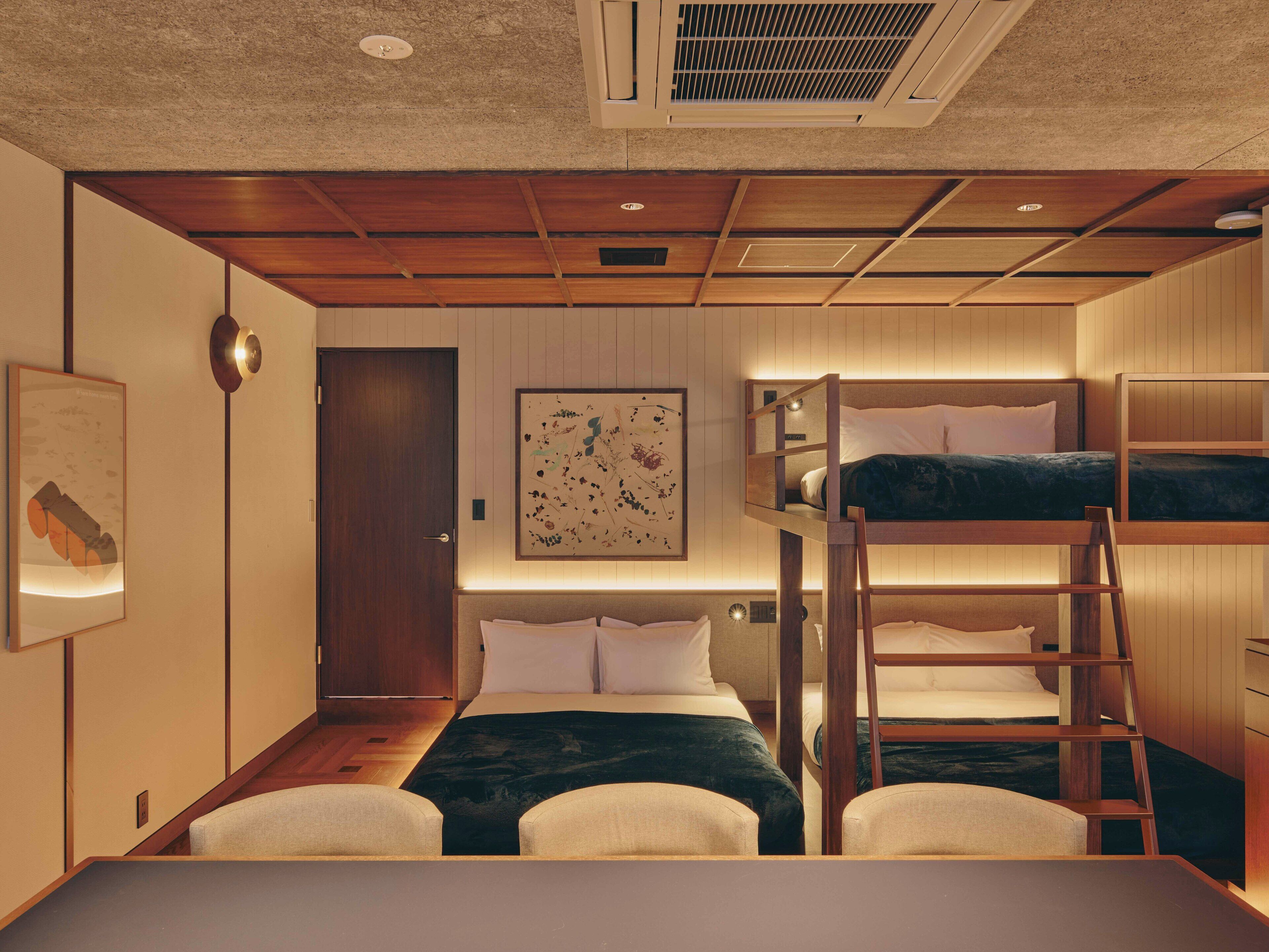 A bunk bed room with a wooden ceiling, a framed artwork on the wall, and a small table in the foreground.