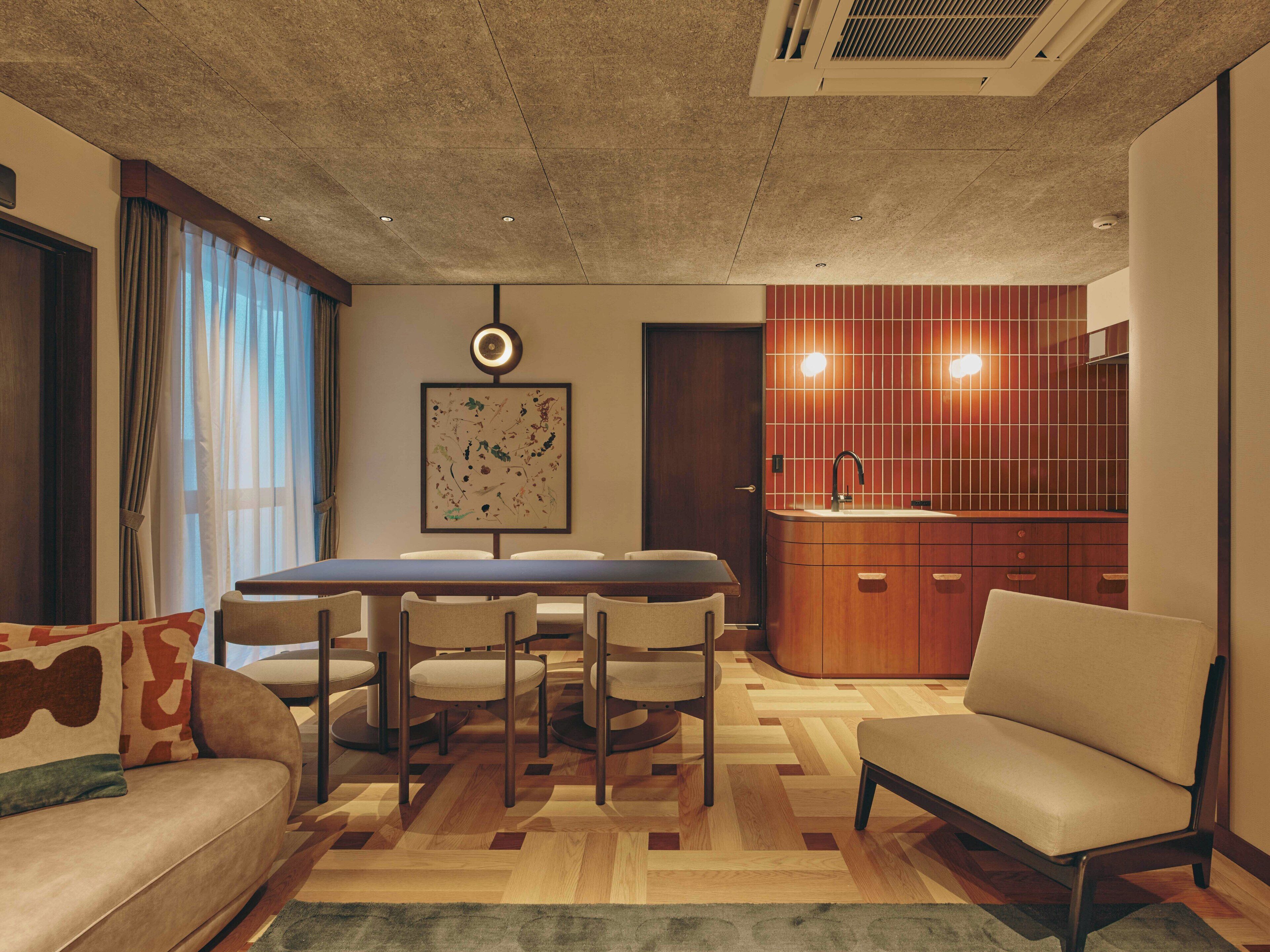 Una sala de estar moderna con una mesa de comedor, sillas, un sofá y una cocina con un lavamanos y armarios.