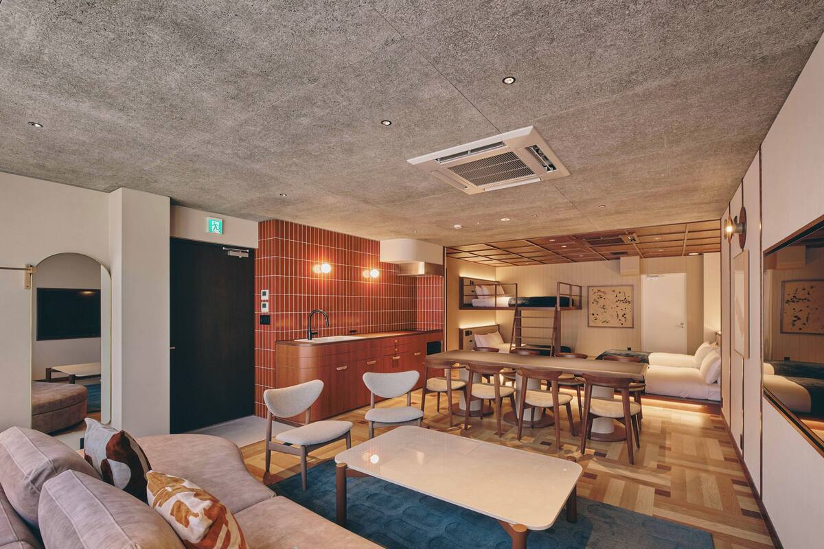 A modern living room with a sofa, coffee table, and a dining area with a table and chairs.