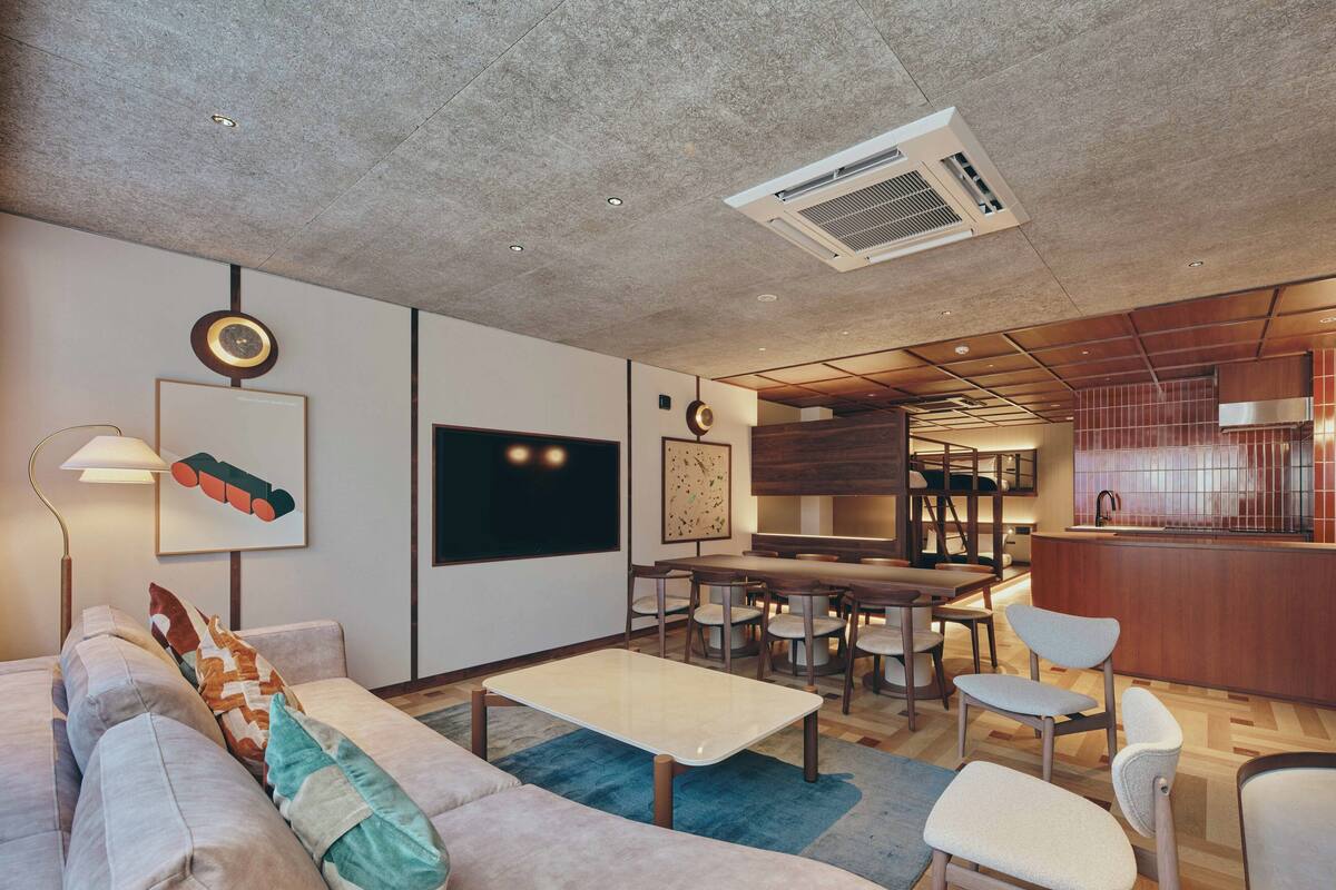 A modern living room with a sofa, coffee table, and chairs, a kitchen area with a bar, and artwork on the walls.