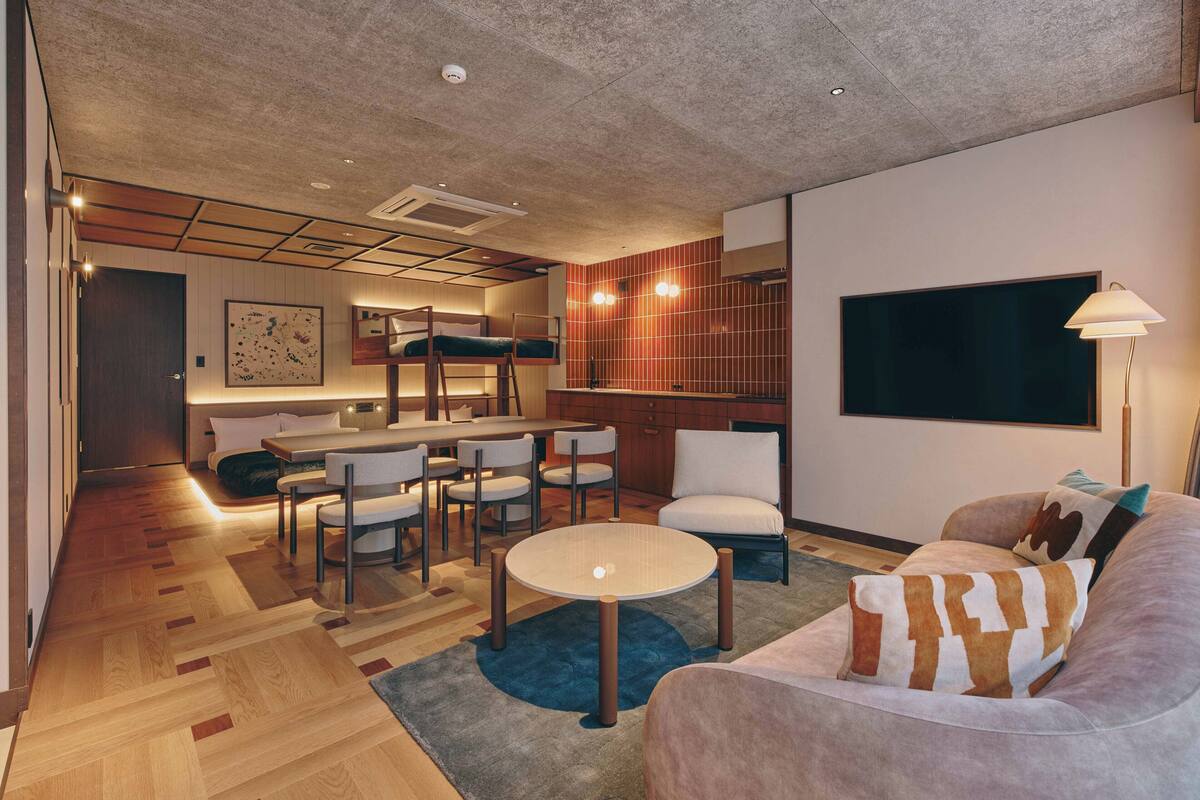 A modern living room with a sofa, coffee table, and a dining area with chairs and a table.