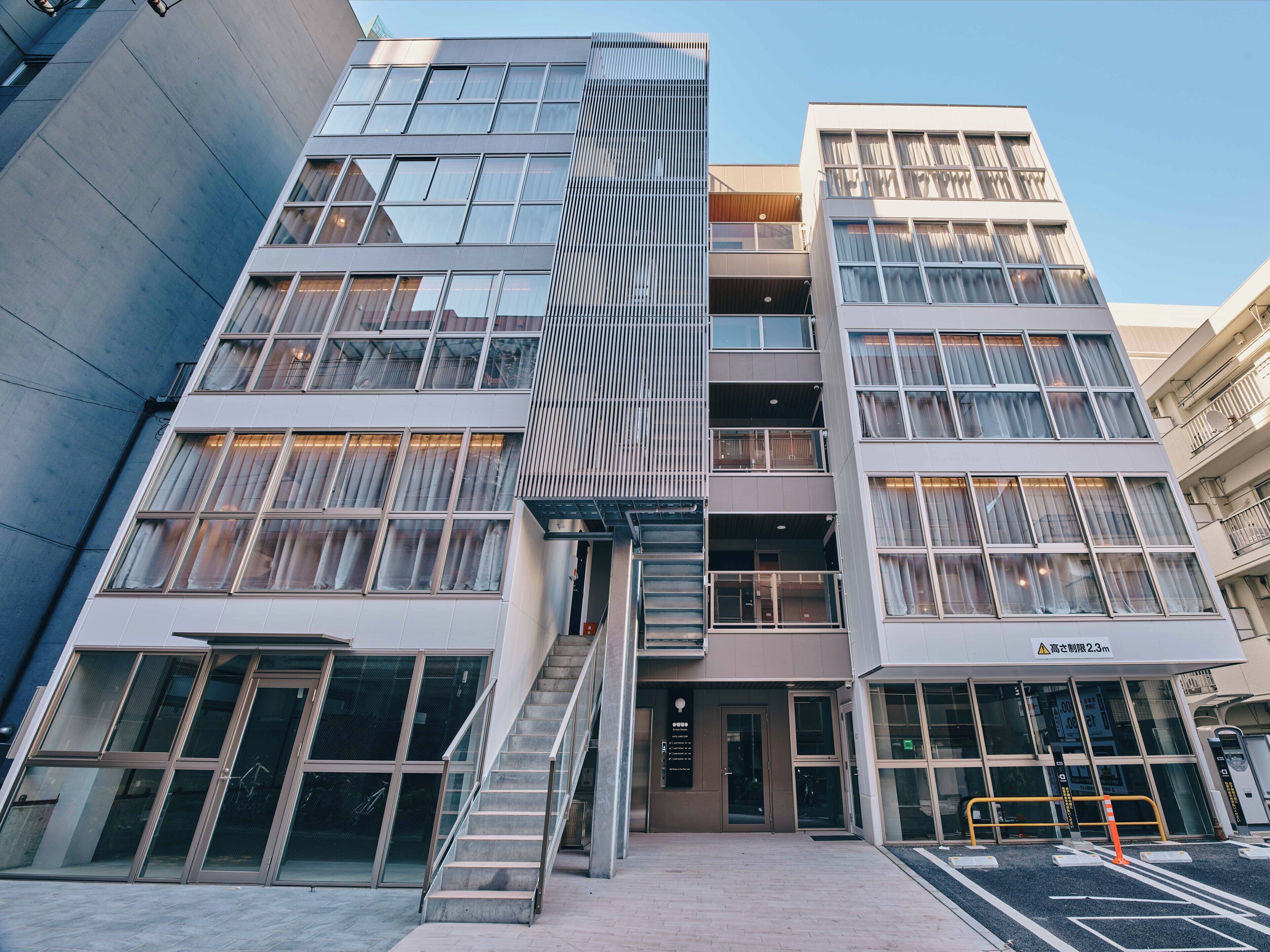 A modern building with multiple floors, large windows, and a staircase leading to the entrance.