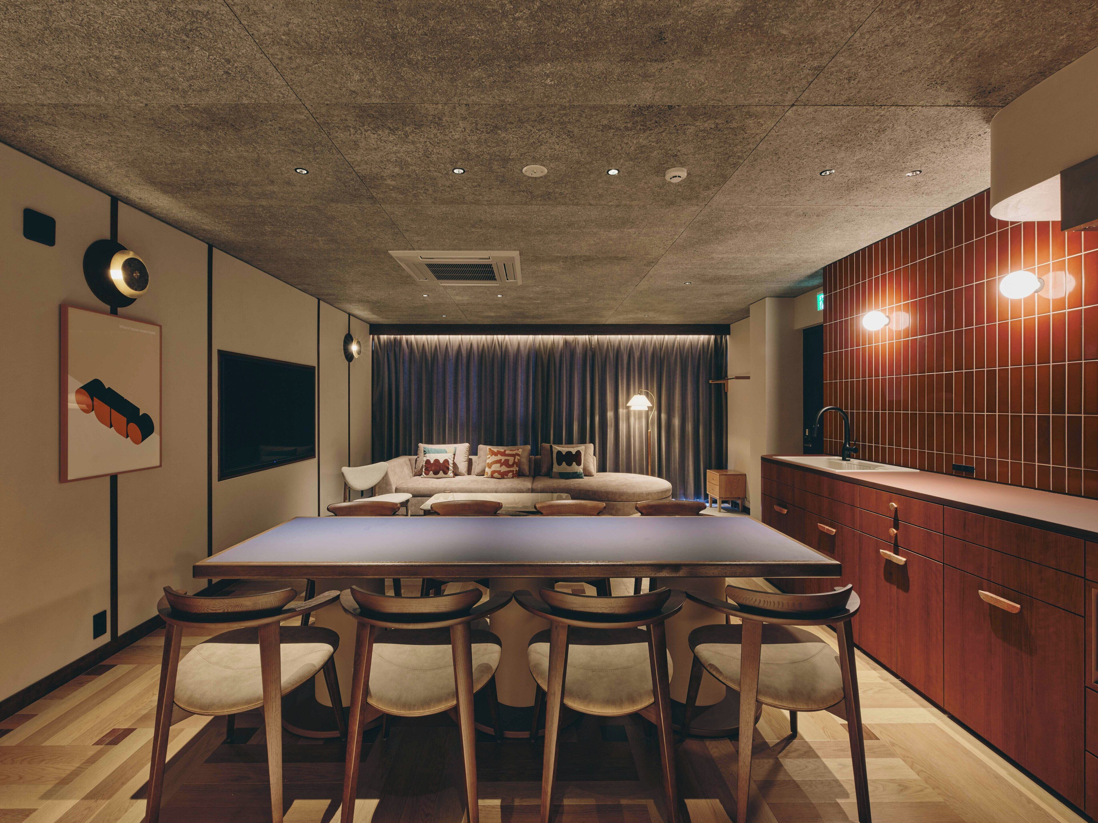 A modern kitchen with a wooden countertop, bar stools, and a dining table.