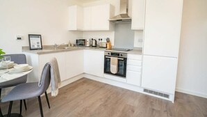A modern kitchen with white cabinets, a built-in oven, a microwave, and a kettle. - Charming 2BED Apartment in the Heart of Nottingham (Nottingham)