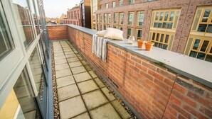 A rooftop terrace with a brick wall, a white ledge, and a view of adjacent buildings. - Charming 2BED Apartment in the Heart of Nottingham (Nottingham)