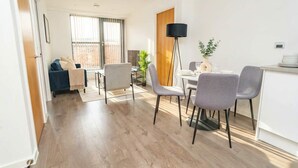 A modern living room with a sofa, dining table, chairs, and a floor lamp. - Charming 2BED Apartment in the Heart of Nottingham (Nottingham)