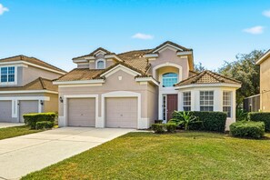 A two-story house with a beige facade, a front garage, and a well-maintained lawn. - Disney Escape – 5-Bed Villa with Pool (Kissimmee)