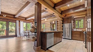 L’intérieur d’une cabane en rondins comprend une cuisine, un coin repas et de grandes fenêtres.