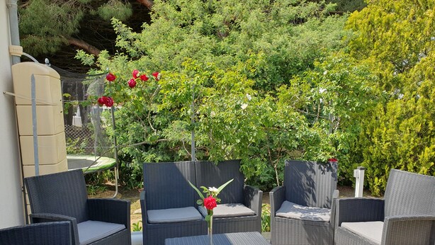 Un espace extérieur aménagé avec des meubles en osier et un sol carrelé.