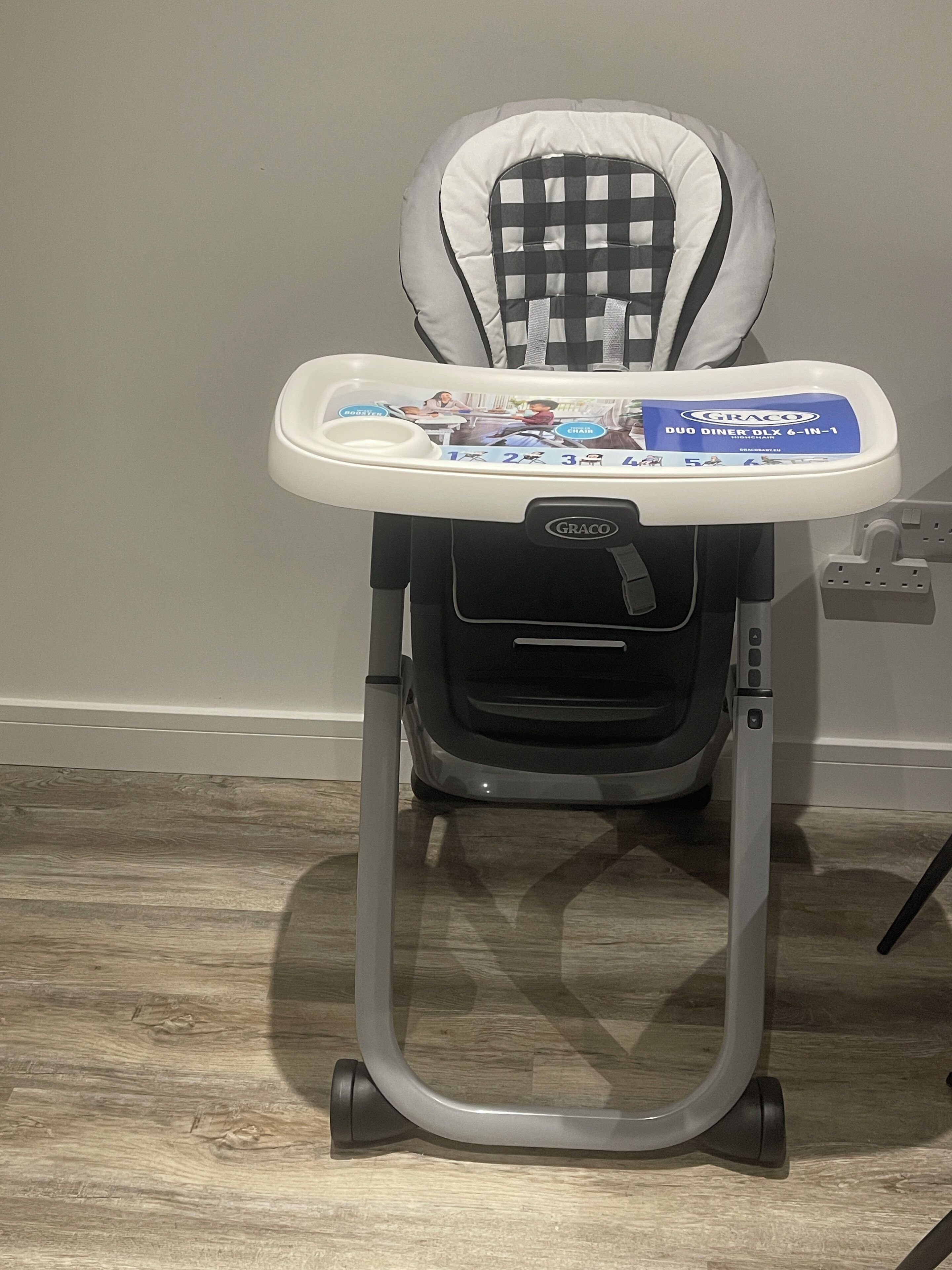 A Graco Duo Diner 6-in-1 stroller with a tray table and a checkered backrest.