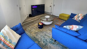 Un salon moderne avec des canapés bleus, une table basse en verre et un téléviseur à écran plat.