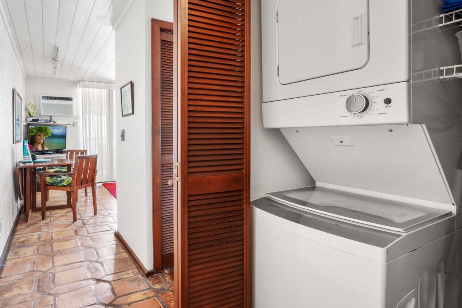 A laundry room with a washing machine and dryer, a wooden door, and a dining area with a table and chairs.