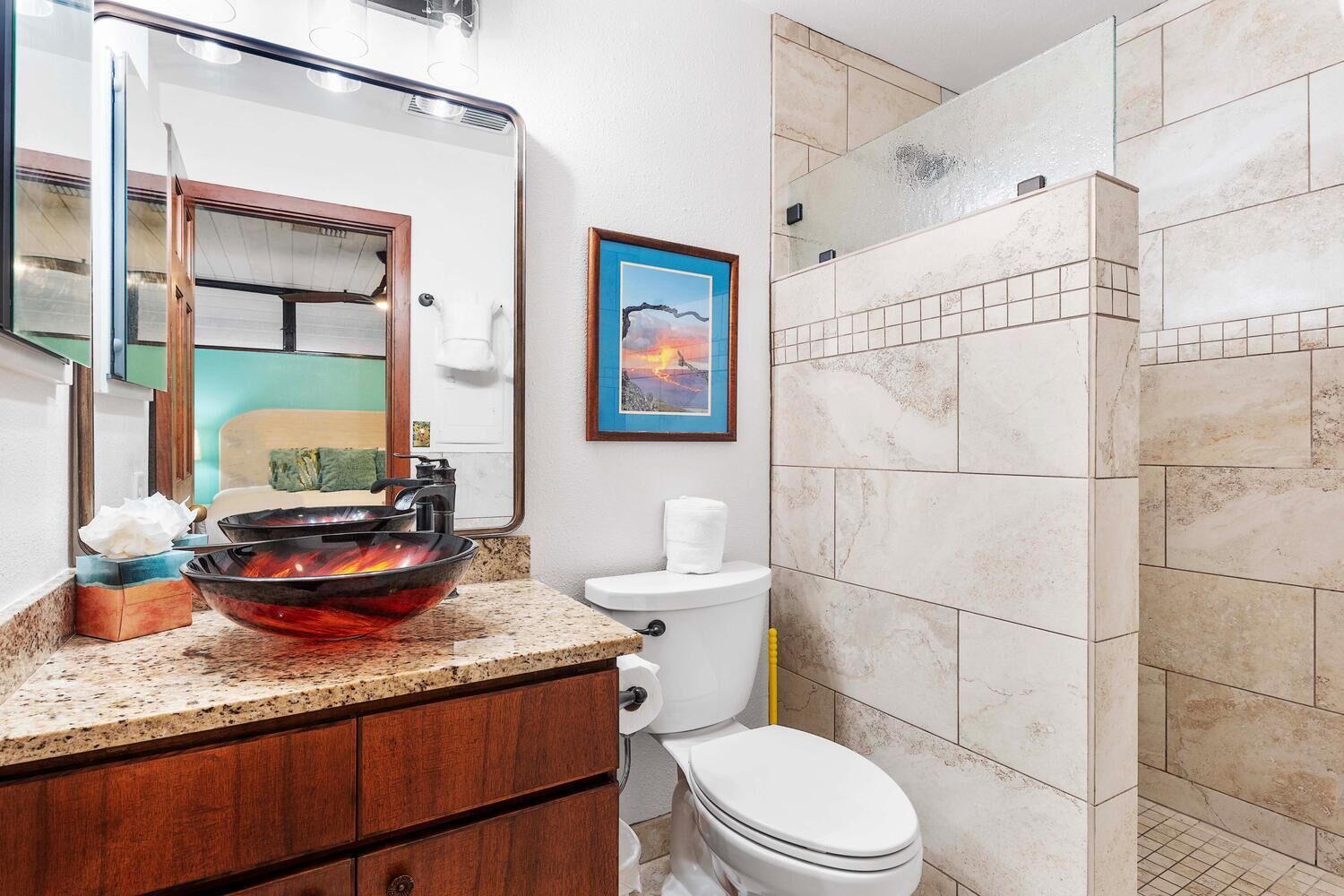 A bathroom with a glass bowl sink, a toilet, and a shower area.