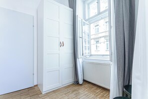 Ein Zimmer mit einem weißen Kleiderschrank, einem Vorhangfenster und einer Heizung.