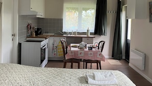 Uma cozinha compacta com área de refeições, uma pequena geladeira e uma janela com cortinas.