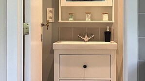 Casa de banho com toucador branco, espelho e chão estampado.
