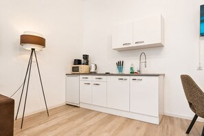 Eine moderne Küche mit weißen Schränken, einer Kaffeemaschine, einem Wasserkocher und einem Spülbecken.