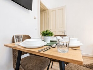 A dining table set with plates, glasses, cutlery, and a potted plant. - Cozy 1BR Haven Perfect for Long Stay (Vienna)