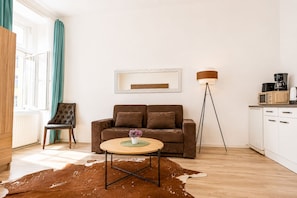 A modern living room with a brown sofa, a round coffee table, and a cowhide rug. - Cozy 1BR Haven Perfect for Long Stay (Vienna)